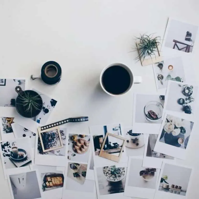 Tazas y fotos impresas en un escritorio de estilo minimalista con plantas decorativas.