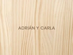 Diseño de álbum de fotos personalizado con nombres Adrián y Carla sobre fondo de madera natural.