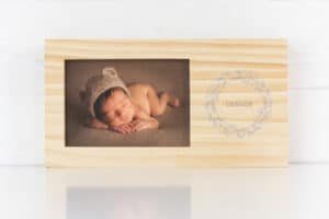 Dibujo del álbum de fotos para recién nacido con la inscripción Carlos enmarcado en madera natural.