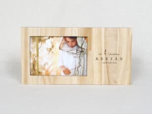 Niño en primera comunión en marco de madera grabado con nombre y evento.