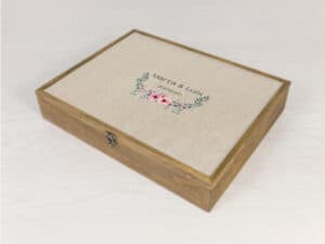 Álbum personalizado de madera con portada de tela y diseño floral, ideal para recuerdos y bodas.
