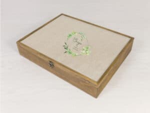 Ámbito: caja de madera para álbumes de fotos con diseño floral y letra elegante en la tapa.