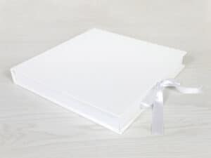 Elegante caja de álbum de fotos blanca con lazo de satén para recuerdos y regalo especial.