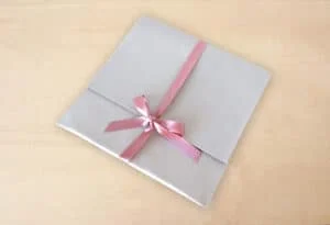 Álbum de fotos decorado con lazo rosado, ideal para recuerdos y ocasiones especiales.
