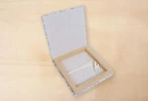Caja de álbumes de fotos con interior forrado y lazos decorativos.