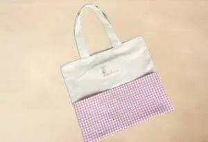 Bolsas de tela personalizadas con diseño de cuadros rosas y logo bordado para álbumes infantiles., diseñada para almacenamiento y regalos.